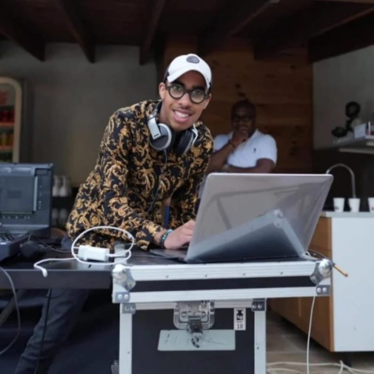 DJ avec un casque autour du cou devant un ordinateur sur un flight case